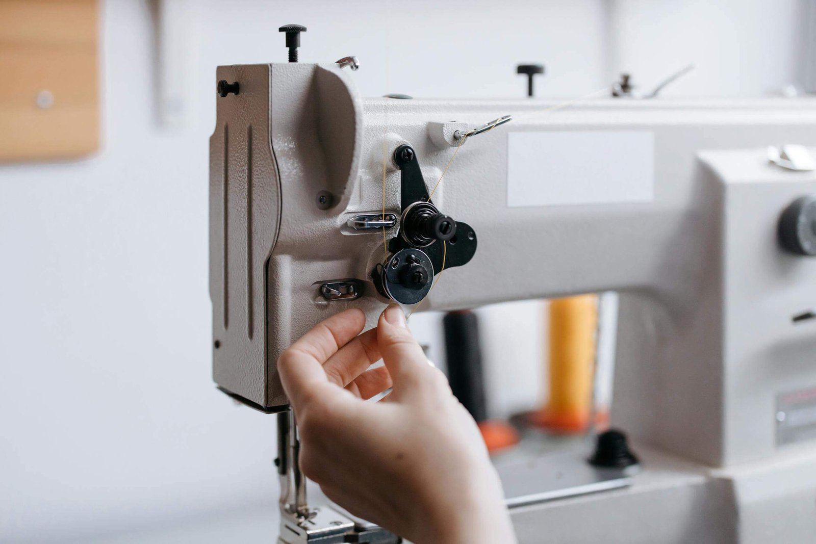 Detailed view of a hand operating a sewing machine with fine thread.